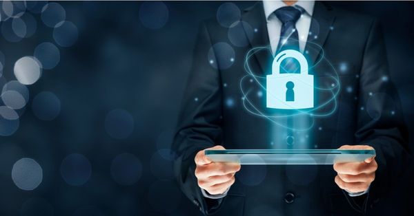 Holographic blue padlock icon floating above a transparent tablet, held by a person wearing a dark suit and tie
