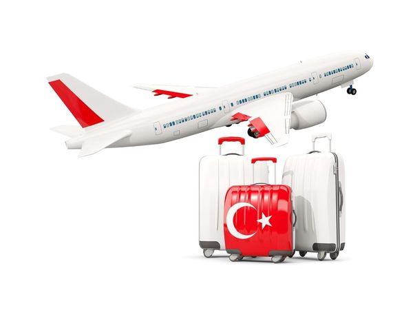 Airplane flying above three white suitcases featuring one red suitcase featuring the Turkish flag, against a white background