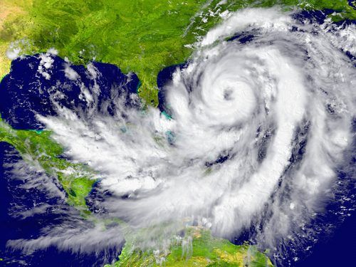 Massive hurricane with distinct spiral structure approaching coastline, satellite view showing white swirling