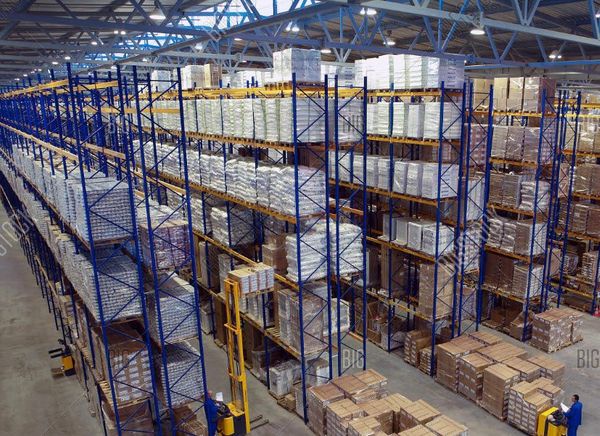 High-ceiling warehouse with blue metal racking systems storing palletized goods