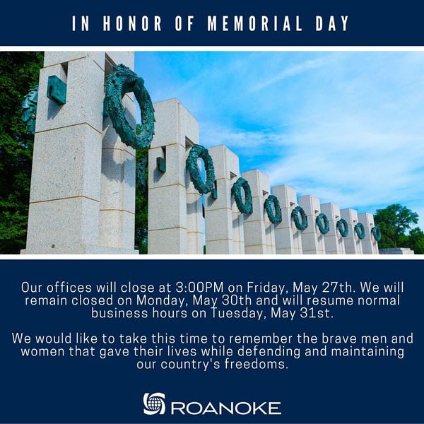 White stone pillars with teal memorial wreaths against a blue sky, honoring fallen military service members on Memorial Day