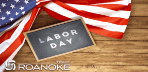 American flag draped beside a small chalkboard with "LABOR DAY" written in white chalk, positioned on a wooden