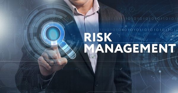 A professional in a suit touches a glowing digital interface with "RISK MANAGEMENT" text, surrounded by futuristic