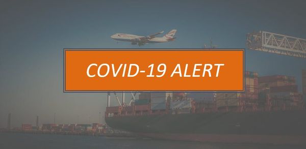 A large orange COVID-19 alert sign overlaid on a cargo port scene with a passenger aircraft flying above shipping
